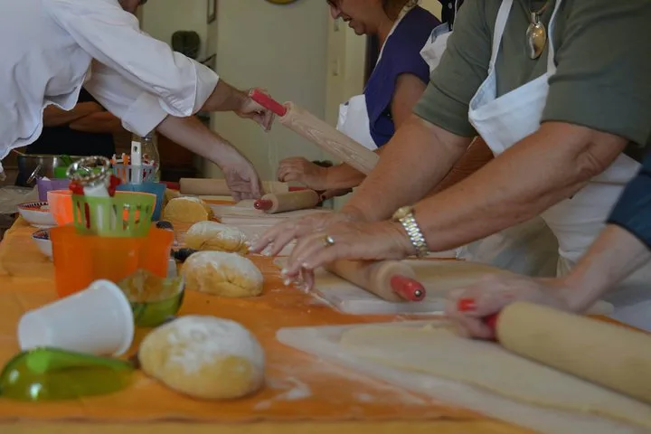 Hands rolling dough with rolling pins on a table