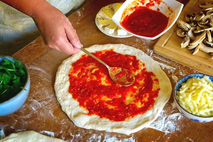 Spreading tomato sauce on a pizza base