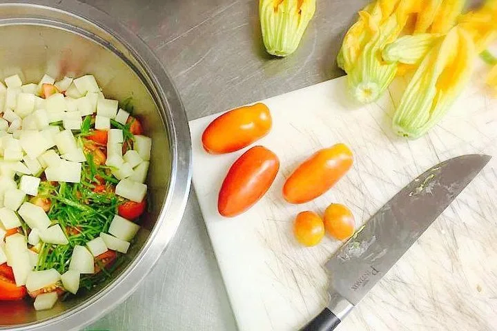 Zucchini flowers, chopped vegetables and tomatoes on a chopping board